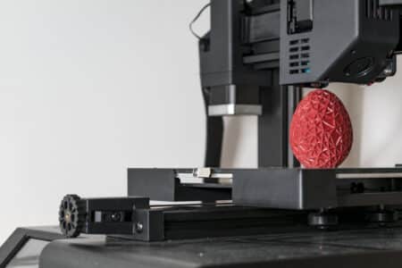98105490 close up of a 3d printer printing a red polygonal egg La evolución histórica de las impresoras hasta la actualidad